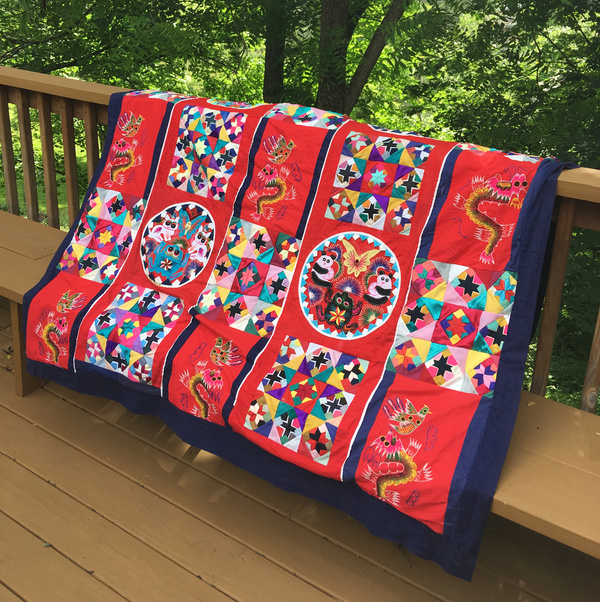 an image of the quilt on the back. four applique circles with frogs, bunnies, pandas, and butterflies are surrounded by squares composed of tiny cross and star patterns and interspersed with machine-embroidered dragon motifs