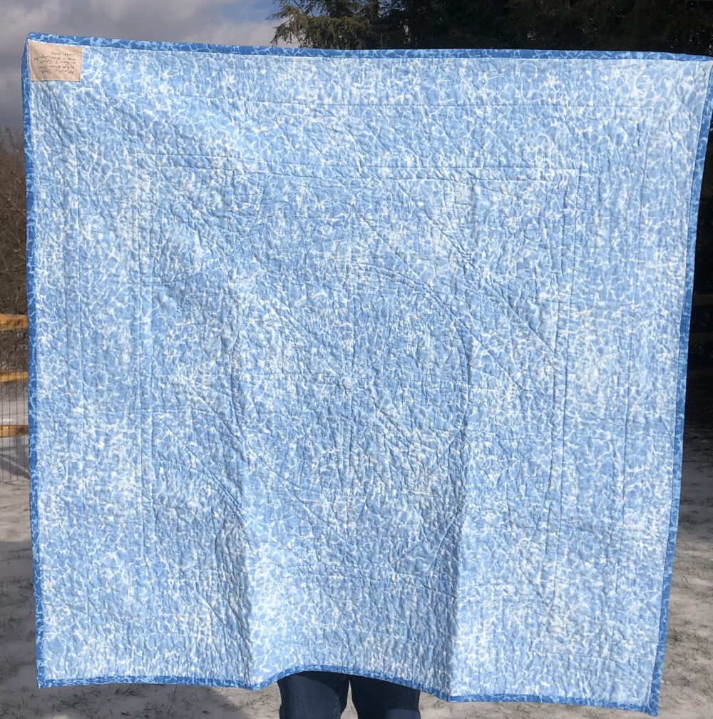 A light rippling water pattern covers the whole back of the quilt. You can kind of see that it’s tightly quilted but not much more detail at this level.