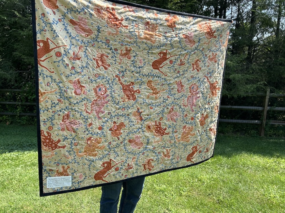 The quilt back fabric is a light tan color with whimsical Asian-inspired dragon and interesting antelope-like and other animals amid vines, etc. It is reminiscent of older tapestries and embroidery.