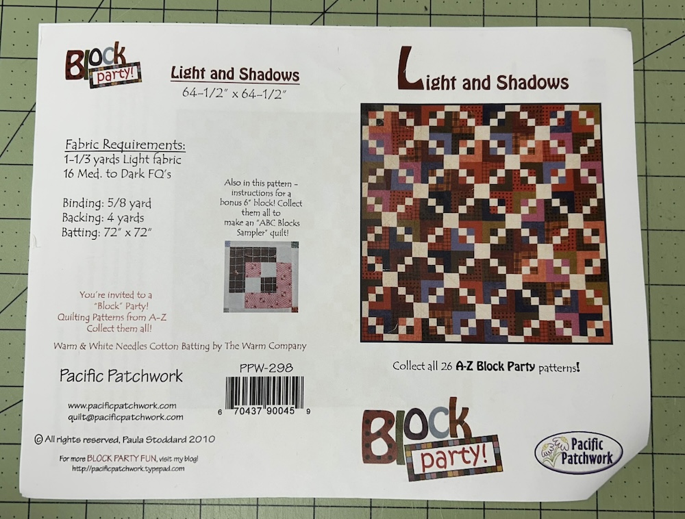 A photograph of the quilt pattern. The actual block is pictured, a four-patch with two light and two darker squares surrounded by larger colorful pieces in a long-cabin-like style with white squared in the corner.